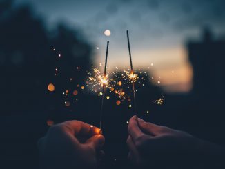 Two hands, sparklers at dusk